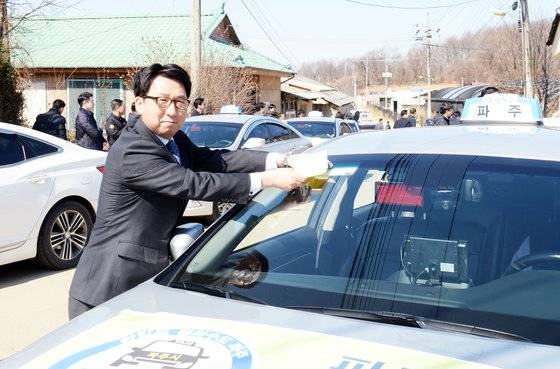 최종환 파주시장이 지난 2019년 4월 1일 ‘천원택시’ 운행식에서 첫번째 운행 택시에 스티커를 붙이고 있다. 파주시
