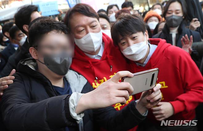 [부산=뉴시스] 하경민 기자 = 국민의힘 윤석열 대선 후보가 이준석 당 대표와 함께 4일 부산 부산진구 서면 일대에서 선거운동을 펼치던 중 한 시민과 셀카를 찍고 있다. 2021.12.04. yulnetphoto@newsis.com