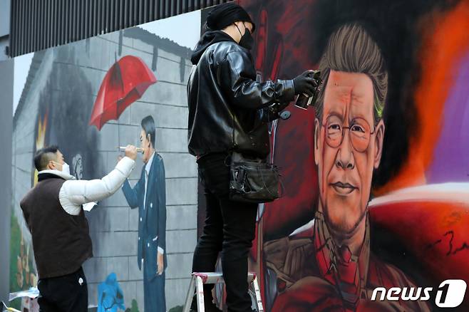 서울 종로구의 한 중고서점 외벽에 더불어민주당, 국민의힘 대선 후보로 보이는 인물들의 새 벽화가 그려지고 있다. /사진제공=뉴스1