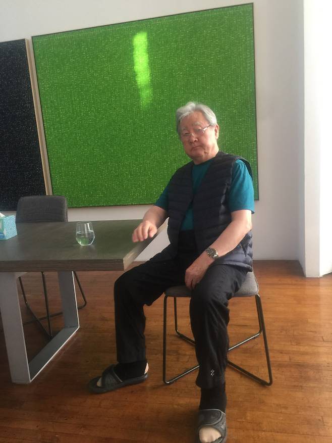 마에자와 유사쿠가 구입 소장하고 있는 ‘WATER YLWG’(17 / 66×82 inches)  작품 앞에 앉아 있는 안영일 작가.