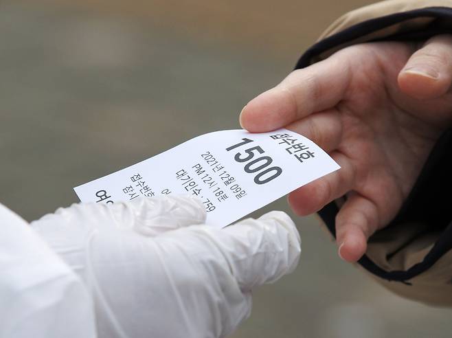 9일 오후 서울 여의도공원 내 문화의 마당에 설치된 임시선별검사소를 찾은 시민이 번호표를 받고 있다./연합뉴스
