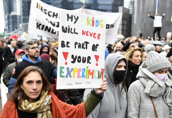 벨기에 브뤼셀에서 지난 5일(현지시간) 정부의 방역조치에 반대하는 시위가 벌어지고 있다. 시위에 참가한 한 여성(왼쪽)이 "내 아이들은 당신의 실험의 일부가 절대 되지 않을 것"이라는 문구를 들고 있다. [AP=연합뉴스]