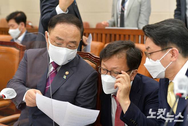 홍남기 경제부총리가 23일 국회에서 열린 기획재정위 전체회의에 출석해 회의 시작에 앞서 이억원 기재부 1차관 등 기재부 관계자와 이야기를 나누고 있다. 윤창원 기자