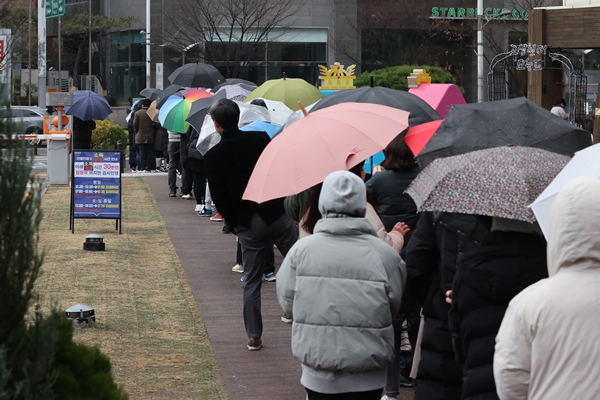10일 오전 서울 송파구보건소 코로나19 선별진료소 앞에 우산을 쓴 시민들이 검사를 받기 위해 줄을 서 있다. 연합뉴스