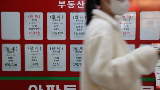 한 시민이 부동산 매물정보가 붙어있는 공인중개업소 게시판 앞을 지나가고 있다. <연합뉴스>