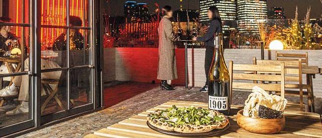 서울 종로구 종로5가 광장시장 내에 위치한 ‘히든 아워’. 입주해 있는 건물 옥상에서 보이는 야경이 이색적이다. 탁자 위의 음식은 오소리감투가 들어간 ‘히든 피자(왼쪽)’와 돼지껍질로 만든 부각. 와인에 쓰인 ‘1905’는 광장시장이 처음 만들어진 연도다. /이신영 영상미디어 기자