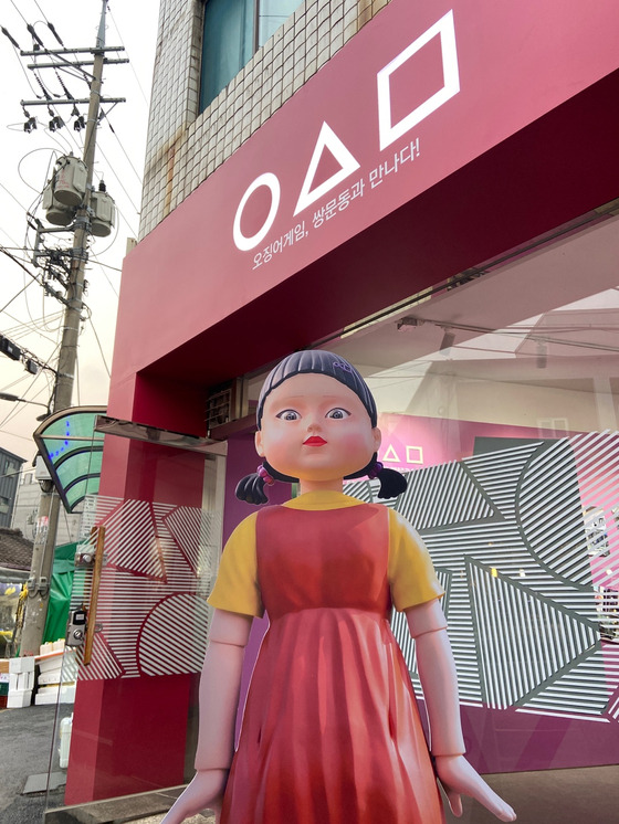 Younghee, the giant robot doll from Netflix's "Squid Game," stands in front of an experience zone set up in Dobong District, northern Seoul, on Tuesday. Visitors can try activities featured on the show, such as making dalgona, a retro candy made by melting sugar, and play marbles. The experience zone is open through January next year. [YONHAP]