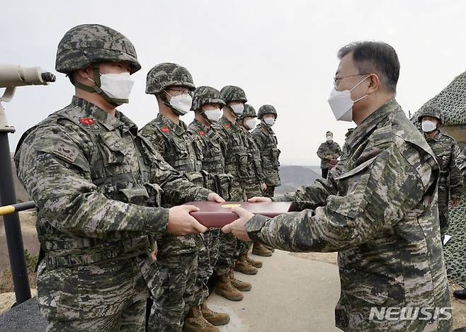 [서울=뉴시스] 문재인 대통령이 23일 오전 서해 백령도 해병대를 방문, 최전방 초소(OP)에서 근무 중인  해병대 장병들을 격려하고 겨울용품 세트를 선물하고 있다. (사진=청와대 제공) 2021.12.23. photo@newsis.com