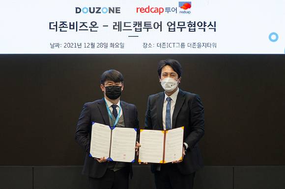 더존비즈온과 레드캡투어가 28일 서울 중구 더존을지타워에서 원스톱 비즈니스 솔루션 제공을 위한 ‘출장 관리 시스템 연동 업무협약’을 체결한 가운데, 더존비즈온 ERP사업부문 전충재 상무와(사진 왼쪽) 레드캡투어 이준호 상무가 협약서를 교환하고 있다. [사진=더존비즈온]
