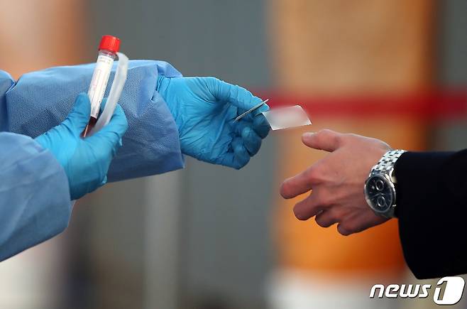 서울역 광장에 마련된 선별진료소에서 의료진이 시민에게 검사키트를 건네고 있다. /뉴스1 © News1 김진환 기자