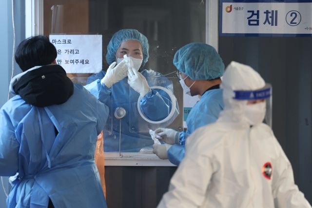6일 오전 서울역 코로나19 임시 선별검사소에서 의료진이 유리벽에 붙은 얼음 조각을 긁어내고 있다. 연합뉴스