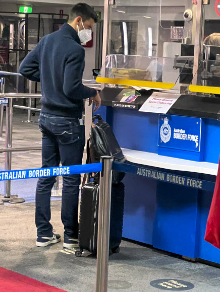 테니스 스타 노바크 조코비치(세르비아)가 지난 5일 호주 멜버른 국제공항에 도착한 뒤 출입국관리소에서 입국 비자가 찍힌 여권이 돌아오길 기다리며 서 있다. 그가 멜버른에 도착한 모습의 사진으로는 8일에야 처음 공개된 것이다. 그가 세르비아에서 비행기를 탈 때만 해도 백신 면제 요건을 충족해 입국 비자가 나올 것이라는 호주오픈 테니스대회 조직위원회의 연락을 받았으나 이곳에서 입국 비자가 취소됐다는 청천벽력 같은 소식을 듣고 지금껏 정부 격리 호텔에 사실상 감금돼 10일 법원 판결을 초조히 기다리고 있다.멜버른 AP 연합뉴스