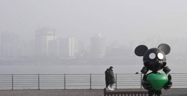 9일 시민들이 서울 여의도 한강공원에 설치된 방독면 쓴 미키마우스 조형물을 지나가고 있다.환경부는 이날 올들어 처음 미세먼지 비상저감조치를 시행했다./ 사진=신경훈 기자