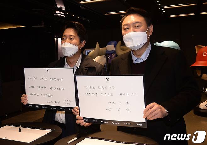 국민의힘 윤석열 대선 후보와 이준석 대표가 12일 서울 종로구 그랑서울타워에서 열린 온라인게임 '리그오브레전드 챔피언스 코리아(LCK) 2022 스프링' 개막전을 관전을 앞두고 작성한 방명록을 들어보이고 있다. 윤 후보는 방명록에 '전설을 만들어가는 대한민국 e스포츠 화이팅' 이라고 적었다. 2022.1.12/뉴스1 © News1 국회사진취재단
