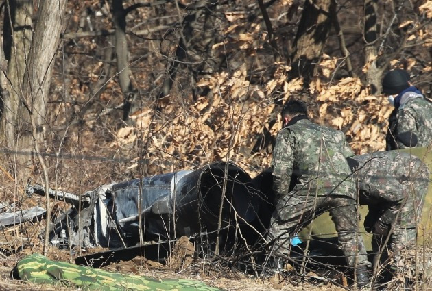 군 관계자들이 12일 경기 화성시의 한 야산에서 전날 추락한 공군 F-5E 전투기 동체 등 현장을 살펴보고 있다./ 연합뉴스