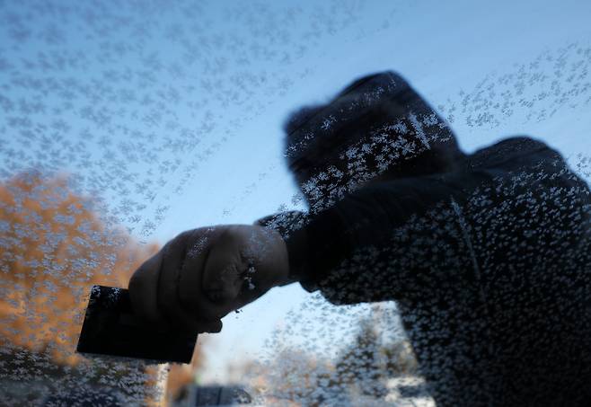 전국 곳곳에 한파특보가 발효 중인 13일 강원 춘천시의 한 사무실 주차장에서 시민이 차창에 낀 성에를 긁어내고 있다. 연합뉴스