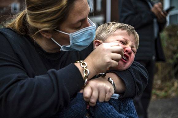 미국에서 새로운 변이인 오미크론의 급속한 확산 탓에 코로나19 신규 확진자가 25만명을 넘어선 가운데 28일(현지시간) 피츠버그 외곽의 스퀴렐 힐 거리에 주차된 검사 차량 앞에서 사라 글릭이 세 살 아들 해리슨이 면봉을 피하자 달래며 콧구멍에 집어넣고 있다. 피츠버그 포스트가제타 AP 연합뉴스