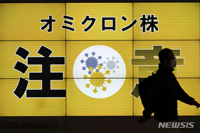 13일 일본 도쿄에서 마스크를 쓴 남성이 오미크론 변이 주의를 알리는 대형 안내판 앞을 지나고 있다. (사진=뉴시스)