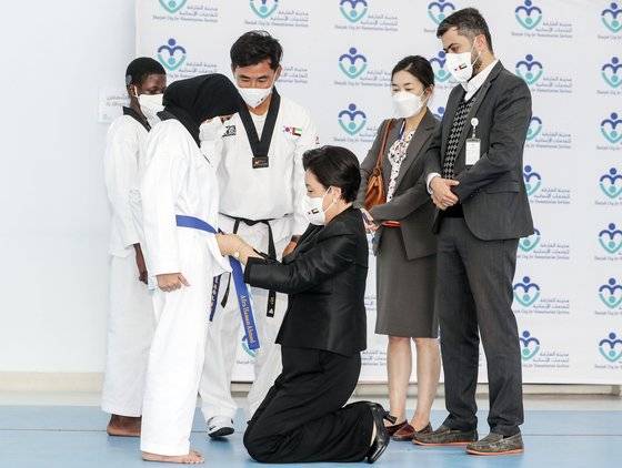 문재인 대통령과 아랍에미리트(UAE)를 방문 중인 김정숙 여사가 17일 오전(현지시각) 샤르자 인도주의 복지센터에서 태권도를 배우는 청각장애 학생에게 한글 이름이 적힌 승급띠를 매주고 있다. 샤르자=김성룡 기자