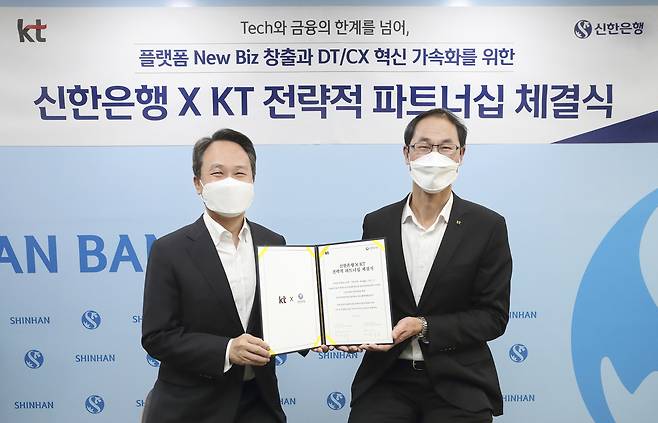 Shinhan Bank CEO Jin Ok-dong (left) and KT’s management planning chief Park Jong-ook pose after signing a partnership deal at the bank’s headquarters in central Seoul on Monday. (KT-Shinhan Bank)