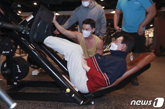 윤석열 국민의힘 대선후보가 18일 오후 서울 강남구 헬스클럽에서 열린 '체력은 국력이다' 실내체육시설 현장 방문 간담회를 마치고 헬스 트레이너의 도움을 받으며 운동을 하고 있다. 2022.1.18/뉴스1 © News1 국회사진취재단