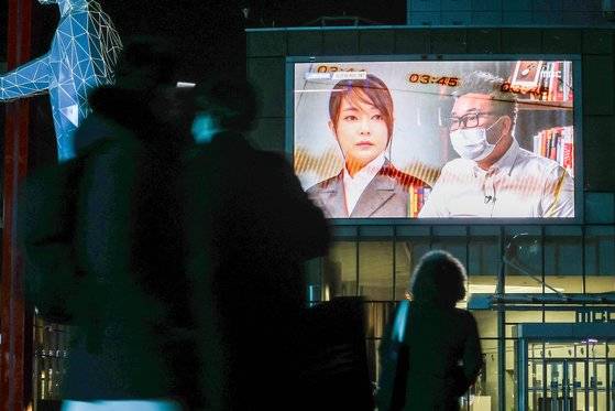 지난 16일 밤 서울 마포구 상암동 MBC 사옥에 걸린 전광판에서 윤석열 국민의힘 대선후보의 배우자 김건희씨의 ‘7시간 전화통화’ 내용을 다룬 MBC 프로그램 ‘스트레이트’가 방영되자 길을 가던 시민들이 지켜보고 있다. [연합뉴스]