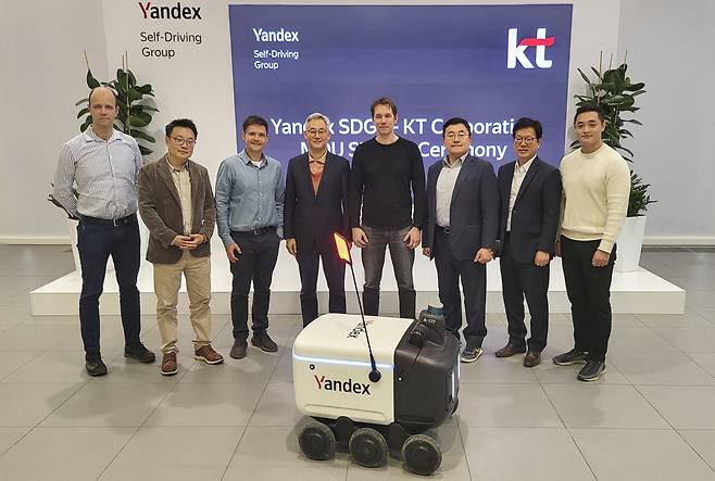 KT‘s AI/DX Convergence Business Division head Song Jae-ho (third from right) and Yandex Self-Driving Group CEO Dmitry Polishchuk (fourth from right) pose for a photo with officials at a signing ceremony held in Moscow, Russia. (KT)