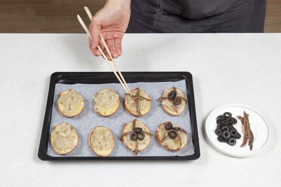 피살라페이스트 대신, 볶은 양파에 안초비를 올려 맛을 냈다. 십자 모양에 블랙 올리브로 포인트를 주면, 접시에 담기만 해도 근사한 홈 파티 사이드디시가 된다. 사진 송미성, 스타일링 스튜디오 로쏘