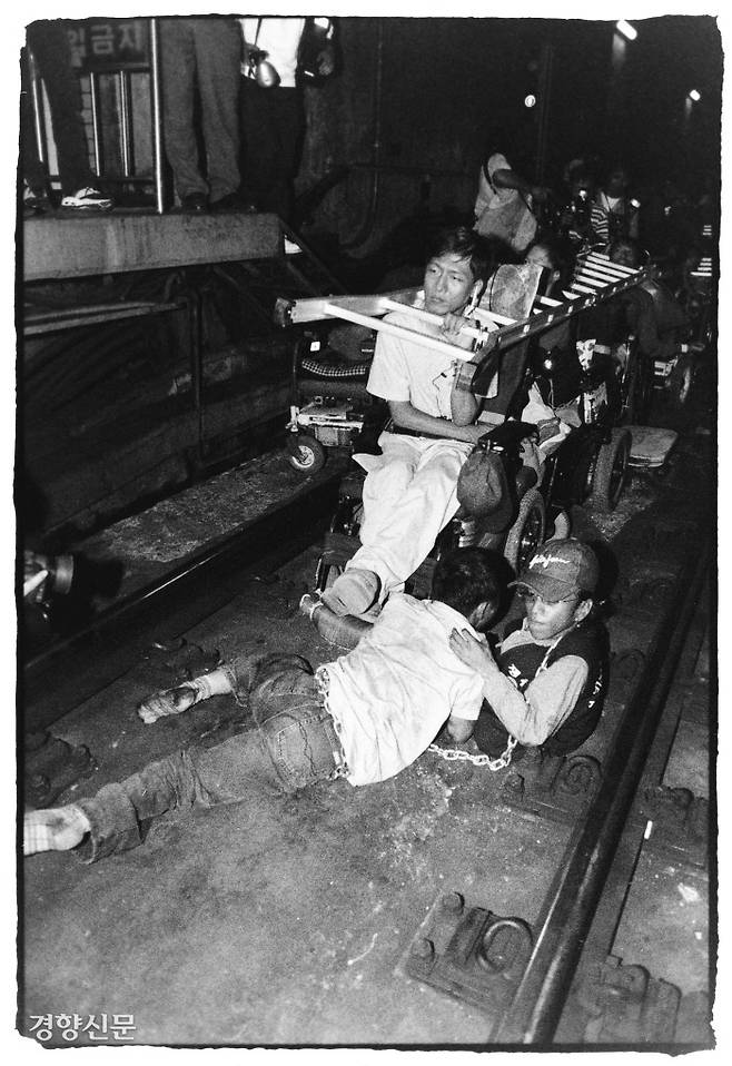 2002년 9월 서울 시청역 지하철 선로에 장애인 활동가들이 내려갔다. 사다리를 목에 걸고, 활동가 2명은 쇠사슬로 자신의 몸을 묶고 있다. 사진=이창길