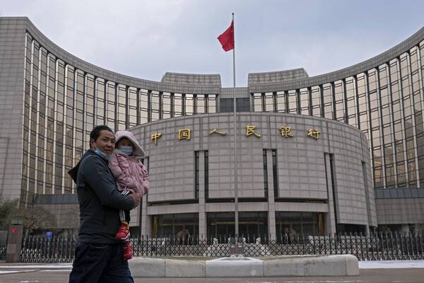 20일 중국 베이징 인민은행 앞을 한 남성이 아이를 안고 지나가고 있다. 베이징/AP 연합뉴스