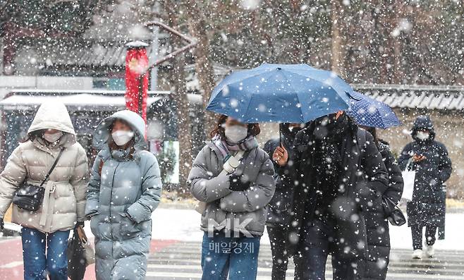 지난 19일 서울 종로구 광화문 광장 일대에서 시민들이 눈을 피해 발걸음을 옮기고 있다. [사진 = 박형기 기자]