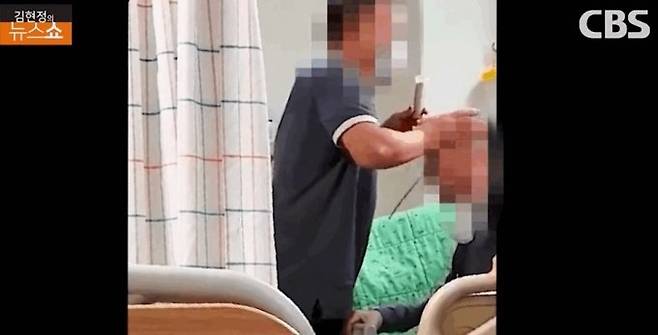 말기암 노인의 머리를 밀치고 있는 간병인의 모습. CBS 뉴스쇼 제보영상