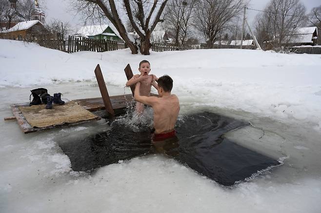 1월 19일 러시아 모스크바 북쪽 쿠판스코예 마을에서 정교회 주현절을 맞아 한 남성이 자신의 아들과 함께 차가운 강물에 몸을 담그고 있다./AP 연합뉴스