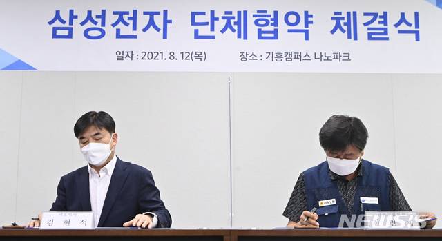 [용인=뉴시스] 김종택기자 = 삼성전자 노사가 창사 이래 처음으로 단체협약을 제정한 12일 오후 경기도 용인시 삼성전자 기흥캠퍼스에서 김현석 대표이사(사진 왼쪽)와 김만재 대표교섭위원이 협약서에 서명하고 있다. 이번 단체협약은 지난해 5월 이재용 삼성전자 부회장이 '무노조 경영 중단'을 선언한 이후 1년 3개월 만의 결실이다. 2021.08.12.jtk@newsis.com