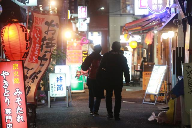 지난 21일 주점과 음식점이 늘어서 있는 도쿄의 거리를 두 사람이 걸어가고 있다. 일본은 22일 신종 코로나바이러스 감염증(코로나19) 확진자 수가 5만 명을 넘었다. 도쿄=AP 연합뉴스