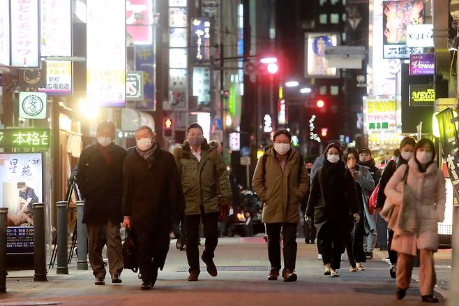 지난 19일 도쿄 시민들이 마스크를 쓴 채 술집과 음식점들이 줄지어 들어선 거리를 따라 걷고 있다. /교도 연합뉴스