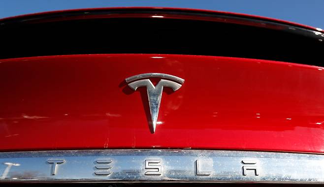 FILE - In this Feb. 2, 2020 file photo, the company logo sits on an unsold 2020 Model X at a Tesla dealership in Littleton, Colo. Tesla Inc. on Wednesday, Jan. 26, 2022 posted record fourth-quarter and full-year earnings as its deliveries soared despite a global shortage of computer chips that has slowed the entire auto industry. The Austin, Texas, company made $5.5 billion last year compared with the previous record year of $3.47 billion in net income posted in 2020. It was the electric vehicle and solar panel maker's third straight profitable year. (AP Photo/David Zalubowski, File)