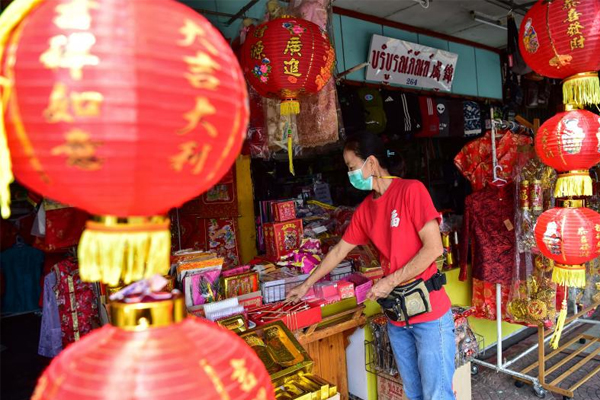A shopkeeper arranges Lunar New Year-themed decorations se she waits for customers in the southern Thai province of Narathiwat on Thursday. (AFP photo)