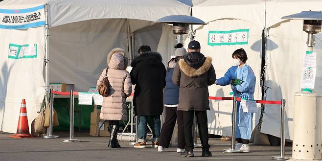설 연휴를 하루 앞둔 28일 오전 김포공항 선별진료소에서 한 의료진이 검사시작을 기다리는 시민들에게 핫팩을 건네고 있다. (사진= 연합뉴스)