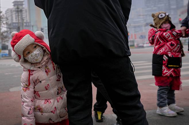 지난 24일 중국 베이징의 중앙업무지구(CBD)에서 어린이가 마스크를 쓴 채 주변을 보고 있다./AP 연합뉴스