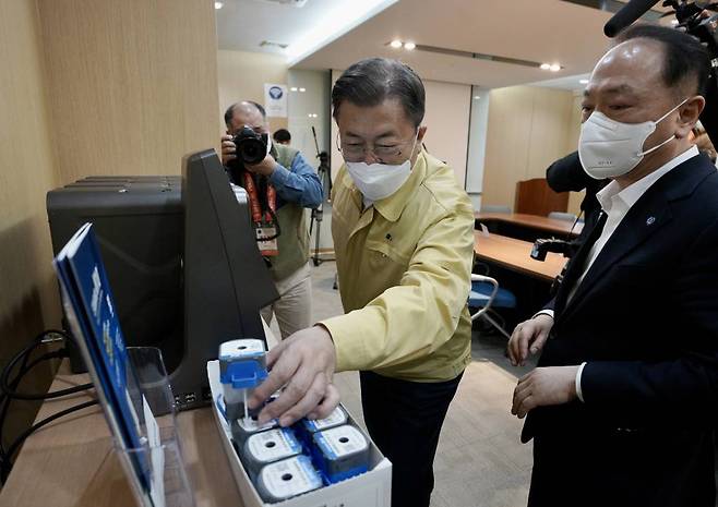 [청주=뉴시스] 전진환 기자 = 문재인 대통령이 30일 오전 충북 청주시 오송읍 코로나19 자가진단키트 생산공장인 SD바이오센서를 찾아 실시간 유전자 증촉 장치에 대한 설명을 듣고 있다. 2022.01.30.