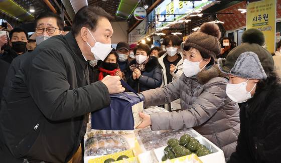 (제주=뉴스1) 구윤성 기자 = 윤석열 국민의힘 대선 후보가 5일 오후 제주 동문시장을 방문해 떡을 구입하고 있다. 2022.2.5/뉴스1