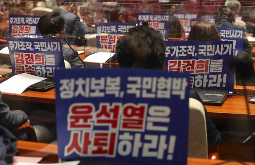 10일 서울 여의도 국회에서 열린 의원총회에 참석한 더불어민주당 의원들의 자리에 ‘윤석열 대선 후보 사퇴 촉구와 부인 김건희 구속 촉구’ 메시지가 적힌 피켓이 붙어 있다.(사진=연합뉴스)