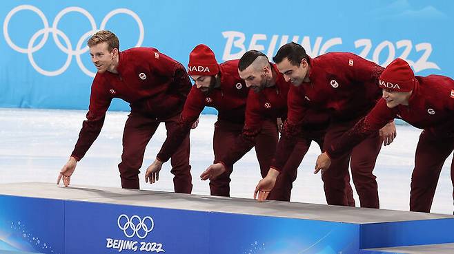 16일 2022 베이징 동계올림픽 쇼트트랙 남자 5000m 계주 결승에서 1위를 차지한 캐나다 대표팀 선수들이 경기 직후 열린 플라워 세리머니에서 금메달 단상에 오르다 바닥을 쓰는 동작을 하고 있다. (사진=연합뉴스)