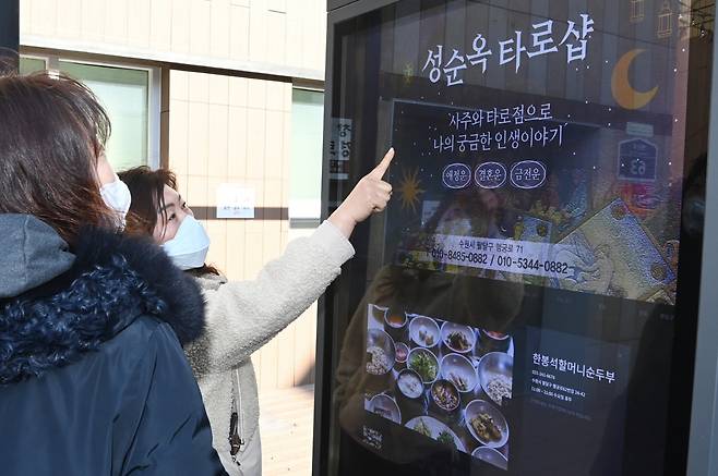 시민들이 수원시 팔달구 남문로데오거리에 설치된 디지털 옥외광고물에 송출되는 지역 업체 광고를 살펴보고 있다. / 사진제공=수원시