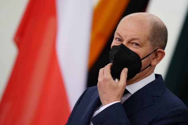 올라프 숄츠 독일 총리가 26일(현지 시각) 마테우시 모라비에츠키 폴란드 총리와 회담을 앞두고 마스크를 고쳐 쓰고 있다. /EPA 연합뉴스