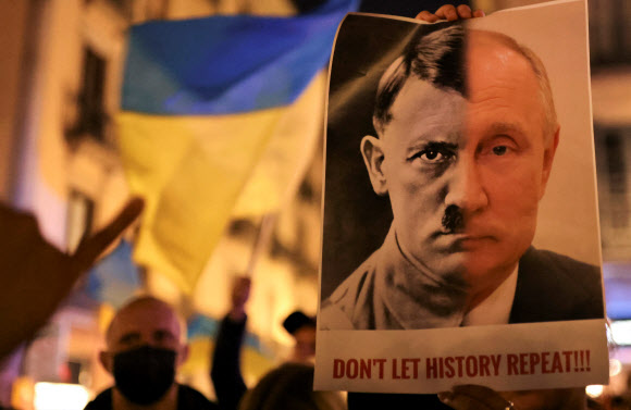 - 24일(현지시간) 스페인 바르셀로나에서 열린 우크라이나 지지 시위에서 한 참가자가 블라디미르 푸틴 러시아 대통령과 나치 독일의 독재자 히틀러의 얼굴을 합성한 사진을 들고 있다. 바르셀로나 로이터 연합뉴스