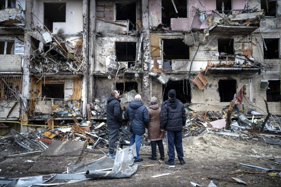 - 우크라이나 시민들이 러시아의 공격으로 무너진 건물을 바라보고 있다. 2022.02.25 AP 연합뉴스
