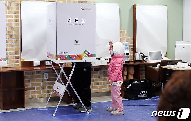 제20대 대통령 선거일인 9일 서울 동대문구 정화여자상업고등학교 별관 헤어미용실습실에 마련된 투표소에서 어린이가 기표소 안 엄마를 궁금해 하고 있다. 2022.3.9/뉴스1 © News1 박지혜 기자