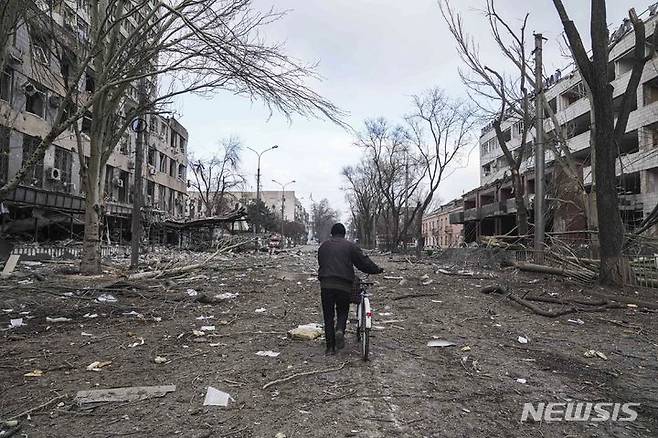 [마리우폴=AP/뉴시스] 10일(현지시간) 러시아군이 우크라이나 마리우폴 주택가에 포격을 가한 후 한 주민이 파손된 거리에서 자전거를 끌고 지나고 있다. 미 국방부 관계자는 "러시아군이  전세를 뒤집기 위해 장거리 포격을 늘리고 있다"라고 전했다. 2022.03.11.
